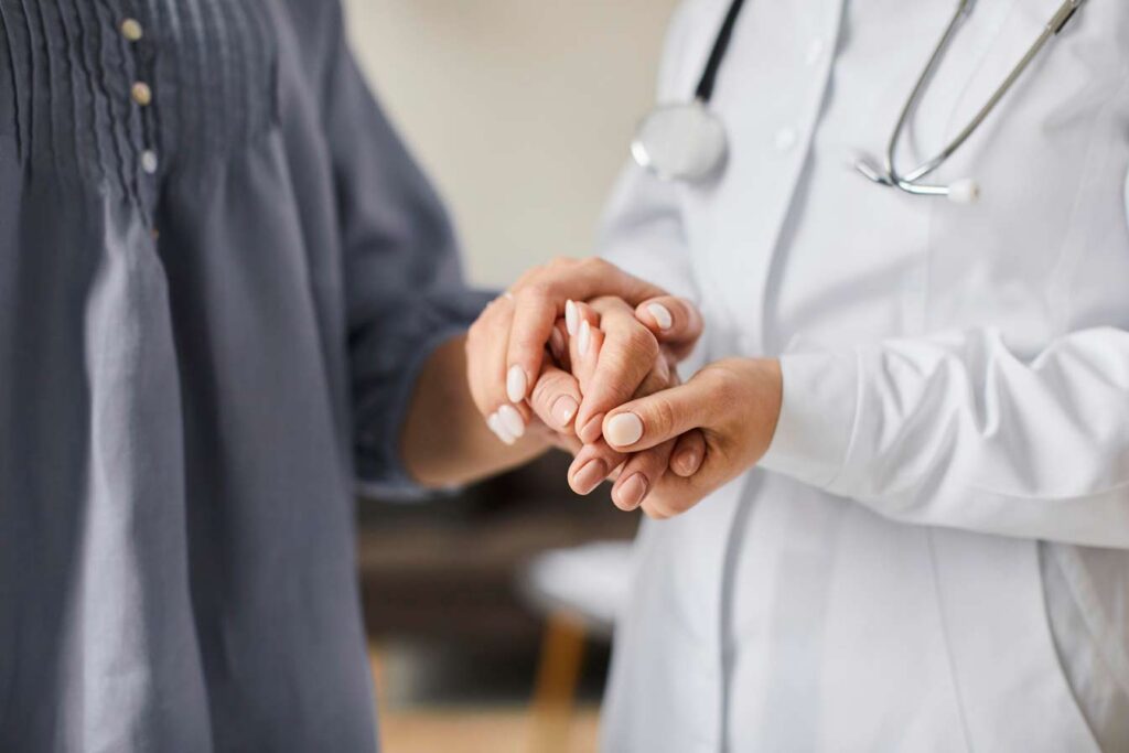 Compassionate doctor holding a patient's hands during a cancer care consultation