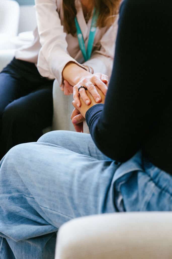 Practitioner gently holding a patient's hands during a supportive consultation